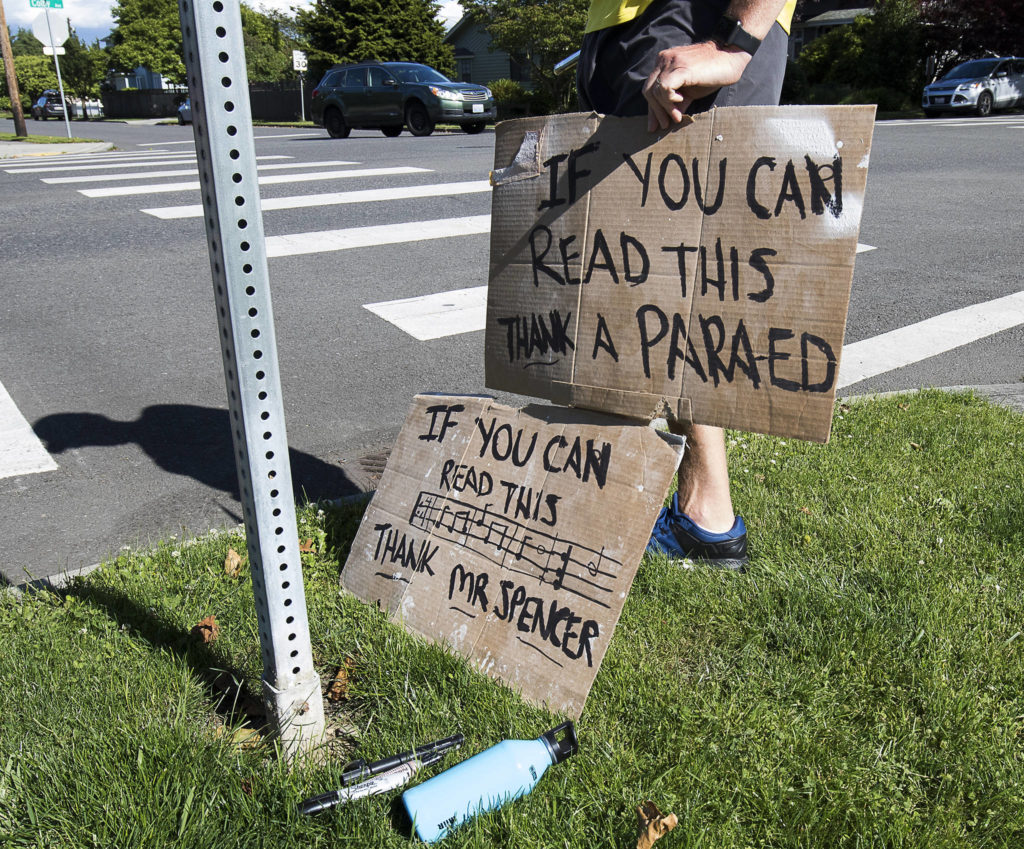 A mans holds signs in thanks Wednesday for music teacher George Spencer and the staff of Whittier Elementary in Everett. (Andy Bronson / The Herald)
