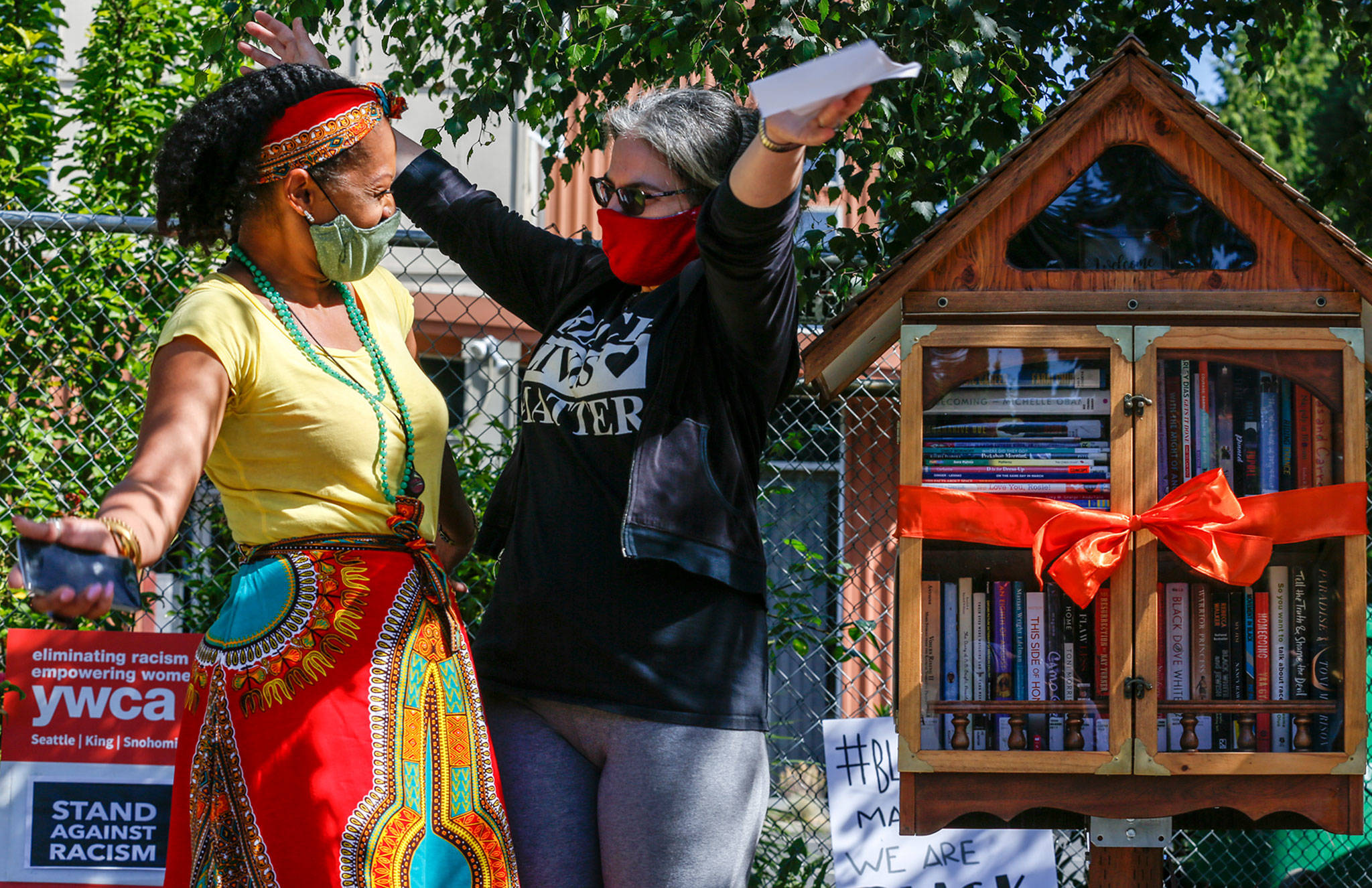 Ashleigh Desvigne-Lee (left) and Sierra Zweig celebrate the dedication of the Little Free Library at the YWCA Pathways for Women in Lynnwood on June 19. (Kevin Clark / The Herald)