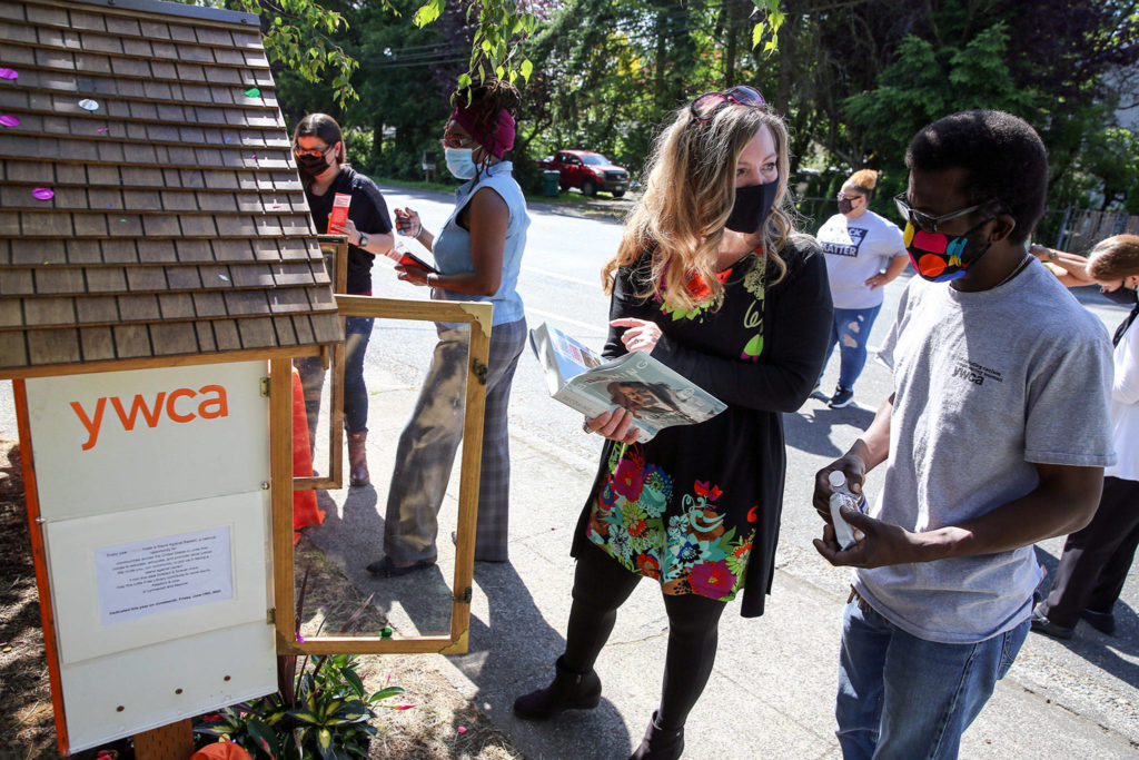 Mary Anne Dillon (left) and Thomas Glass look over a title available at the newly dedicated Little Free Library Friday morning at the YWCA Pathways for Women in Lynnwood. (Kevin Clark / The Herald)
