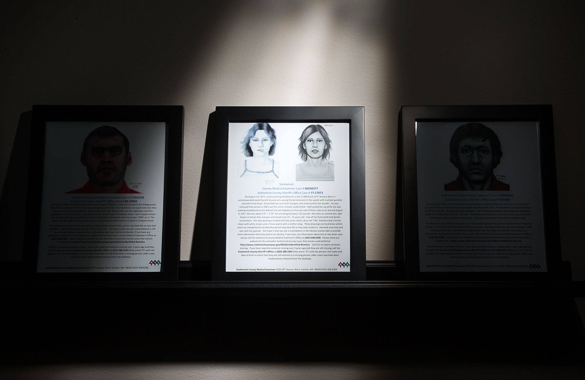 On a shelf at the Snohomish County Medical Examiner’s Office, an artist drawing of a Jane Doe sits among posters of missing persons. (Andy Bronson / The Herald)