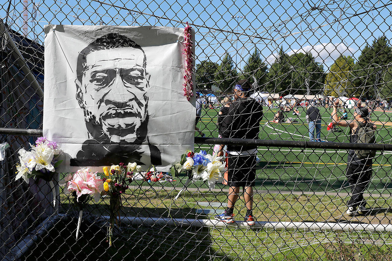 Flowers are placed next to an image of George Floyd on a fence surrounding Cal Anderson Park on Wednesday, inside what has been named the Capitol Hill Occupied Protest zone in Seattle. (AP Photo/Ted S. Warren)