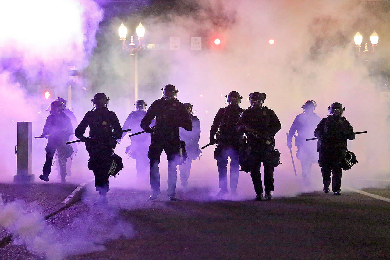In this March 29 photo, police officers walk enveloped by tear gas in Portland, Oregon. (Dave Killen/The Oregonian via AP, File)