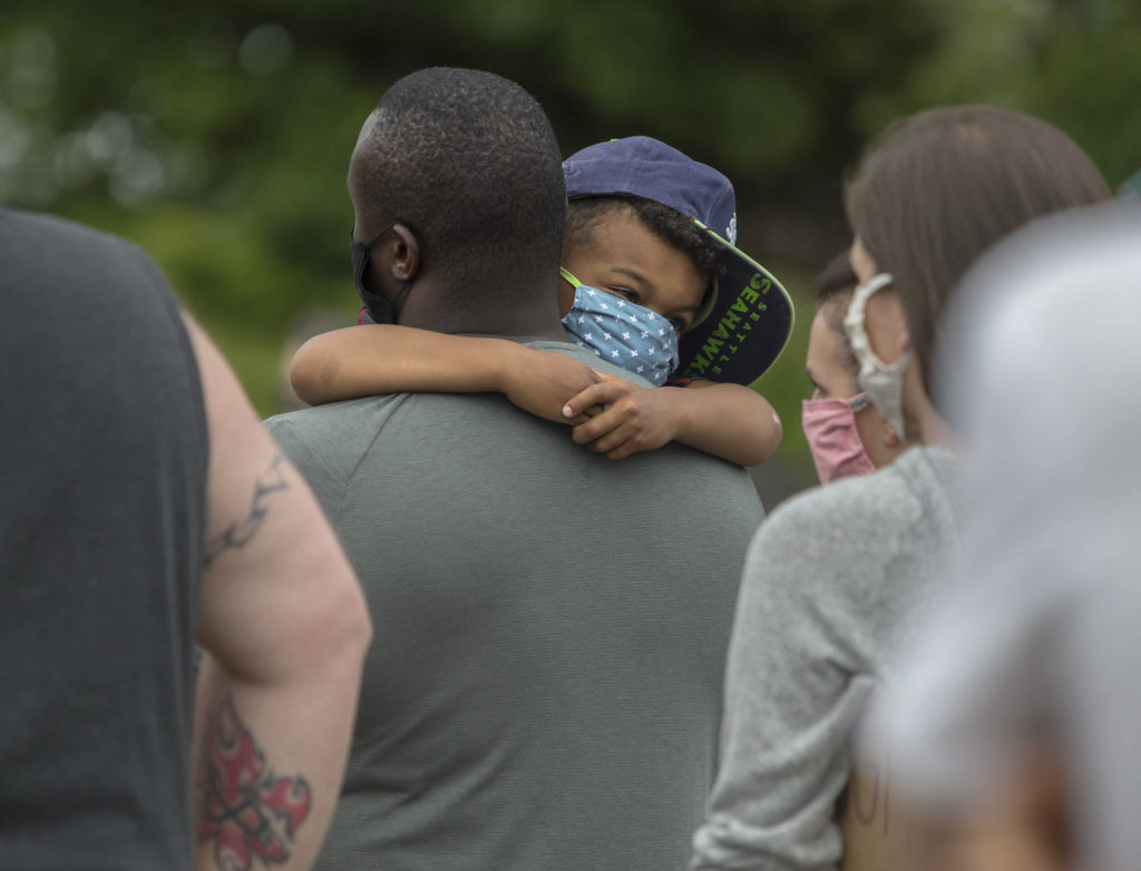 Tieba Broleph holds his son Teo Broleph, 5, while they listen to speakers on Friday, June 19, 2020 in Snohomish, Wa. (Olivia Vanni / The Herald)
