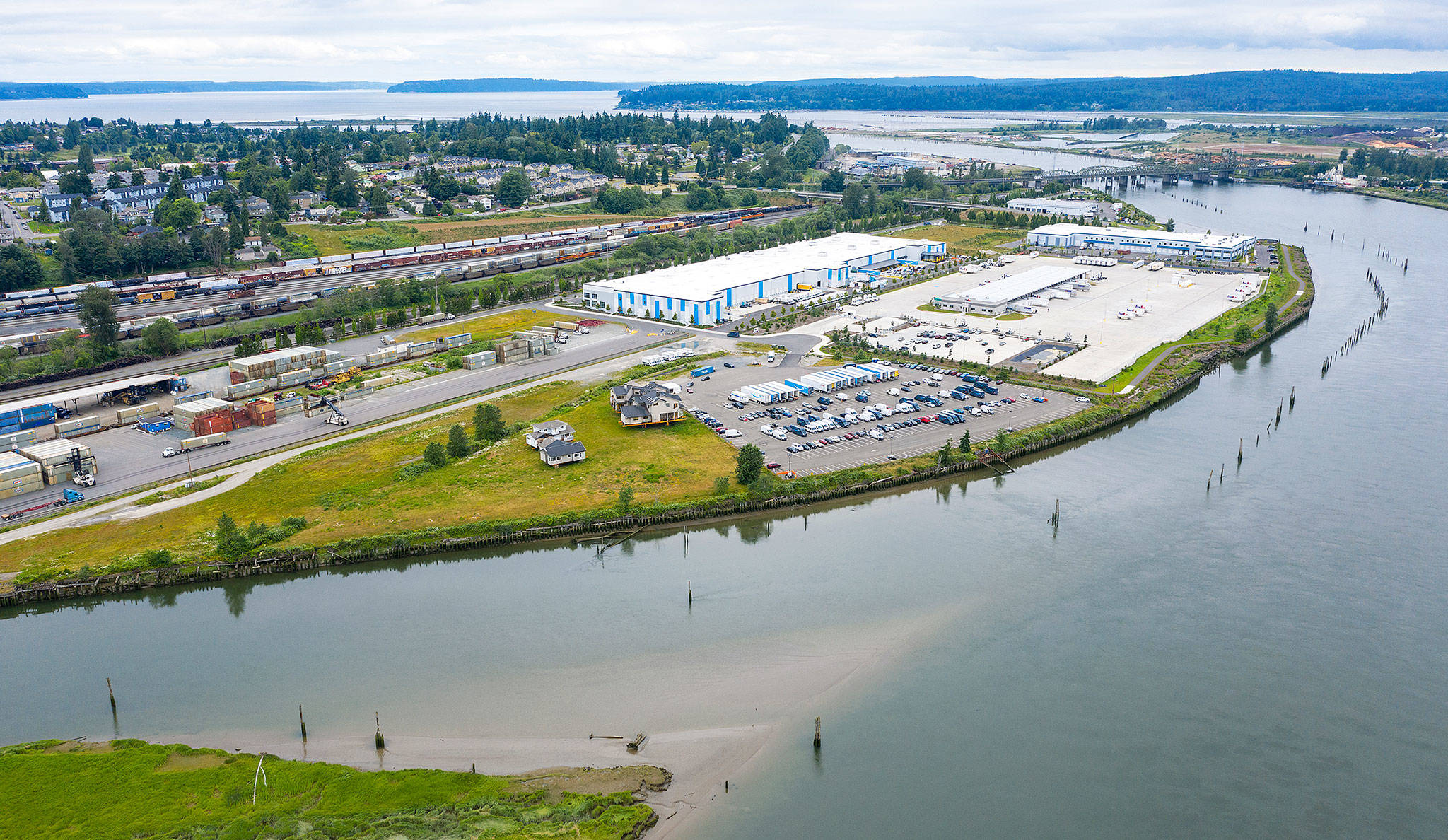 The former site of a Weyerhaeuser mill along the Snohomish River in north Everett is covered by grass and a parking area (center) used by an adjacent Amazon warehouse. (Chuck Taylor / The Herald)