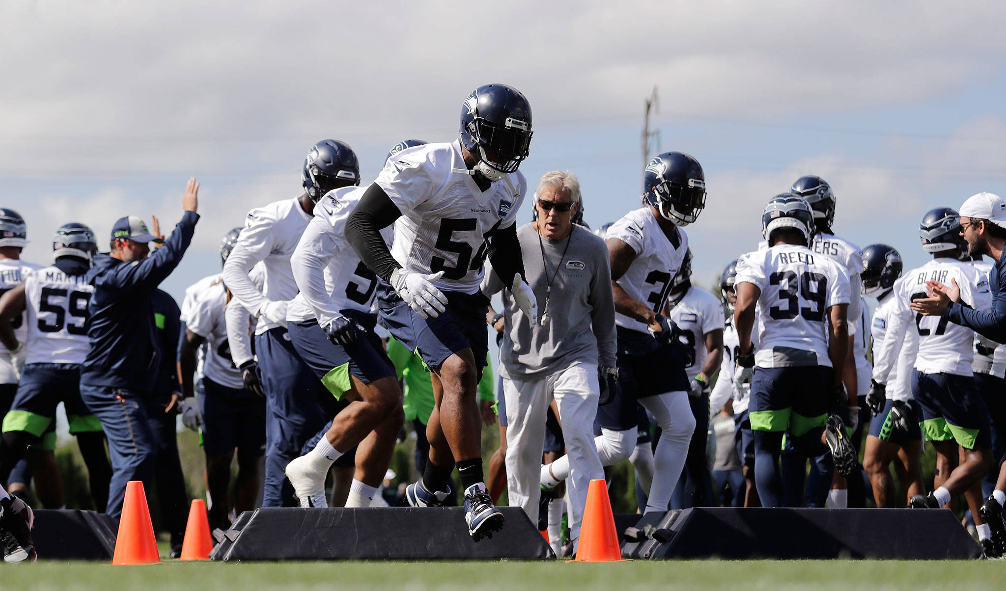 The Seahawks’ Bobby Wagner (54) leads teammates through a drill as head coach Pete Carroll (center right) looks on during training camp in 2019 in Renton. (AP Photo/Elaine Thompson)