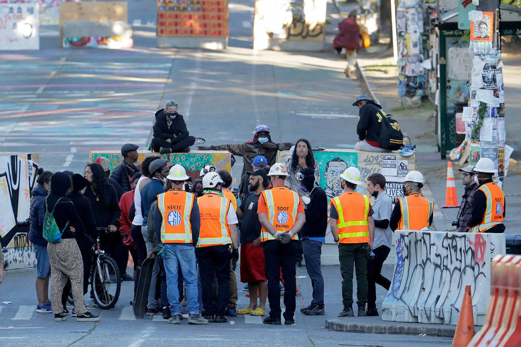 Seattle Department of Transportation workers talk with protest organizers near the Seattle Police Department East Precinct building after SDOT arrived at the the CHOP (Capitol Hill Occupied Protest) zone in Seattle on Friday. (AP Photo/Ted S. Warren)
