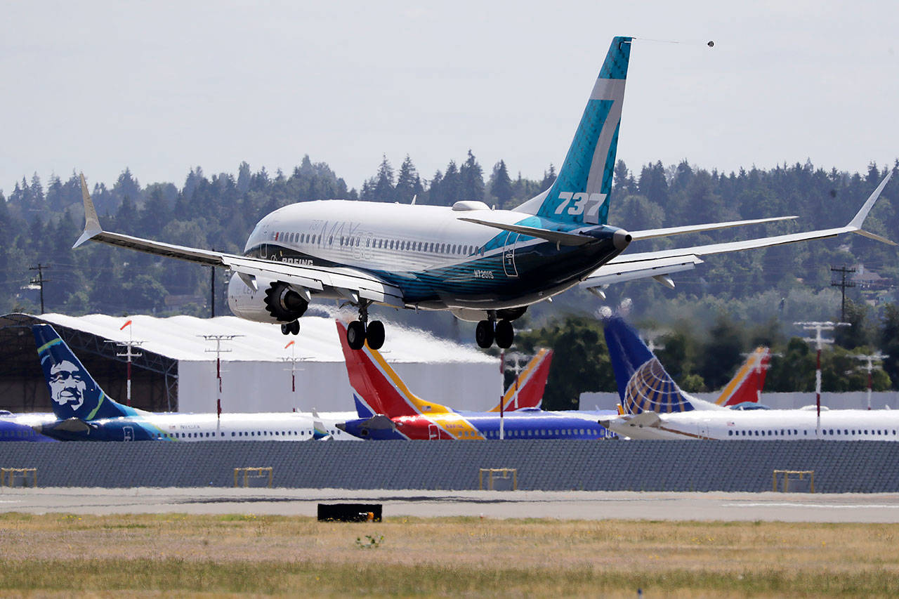 A Boeing 737 Max jet heads to a landing, past other grounded jets at Boeing Field following a test flight Monday in Seattle. (AP Photo/Elaine Thompson)