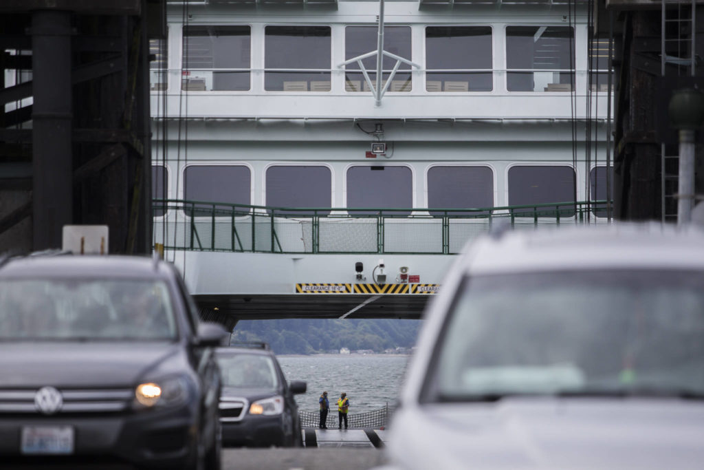 Washington State Ferries workers wait as cars offload in Mukilteo. (Olivia Vanni / The Herald)
