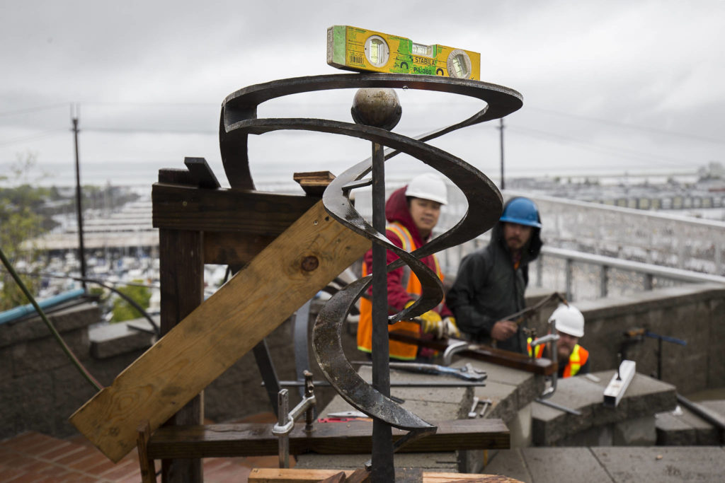 Workers from 12 Avenue Iron check a level Wednesday as they fit railings at the Grand Avenue Park Bridge in Everett. Construction on the new $20 million utility span and walkway is set to wrap by the end of July. (Andy Bronson / The Herald)
