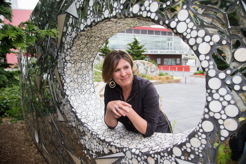 Carol Thomas reminisces about working with artist Linda Beaumont on the Stardust wall at Wetmore Plaza, one of her first projects as Everett’s cultural arts manager. Tuesday was her last day on the job, due to budget cuts. (Andy Bronson / The Herald)
