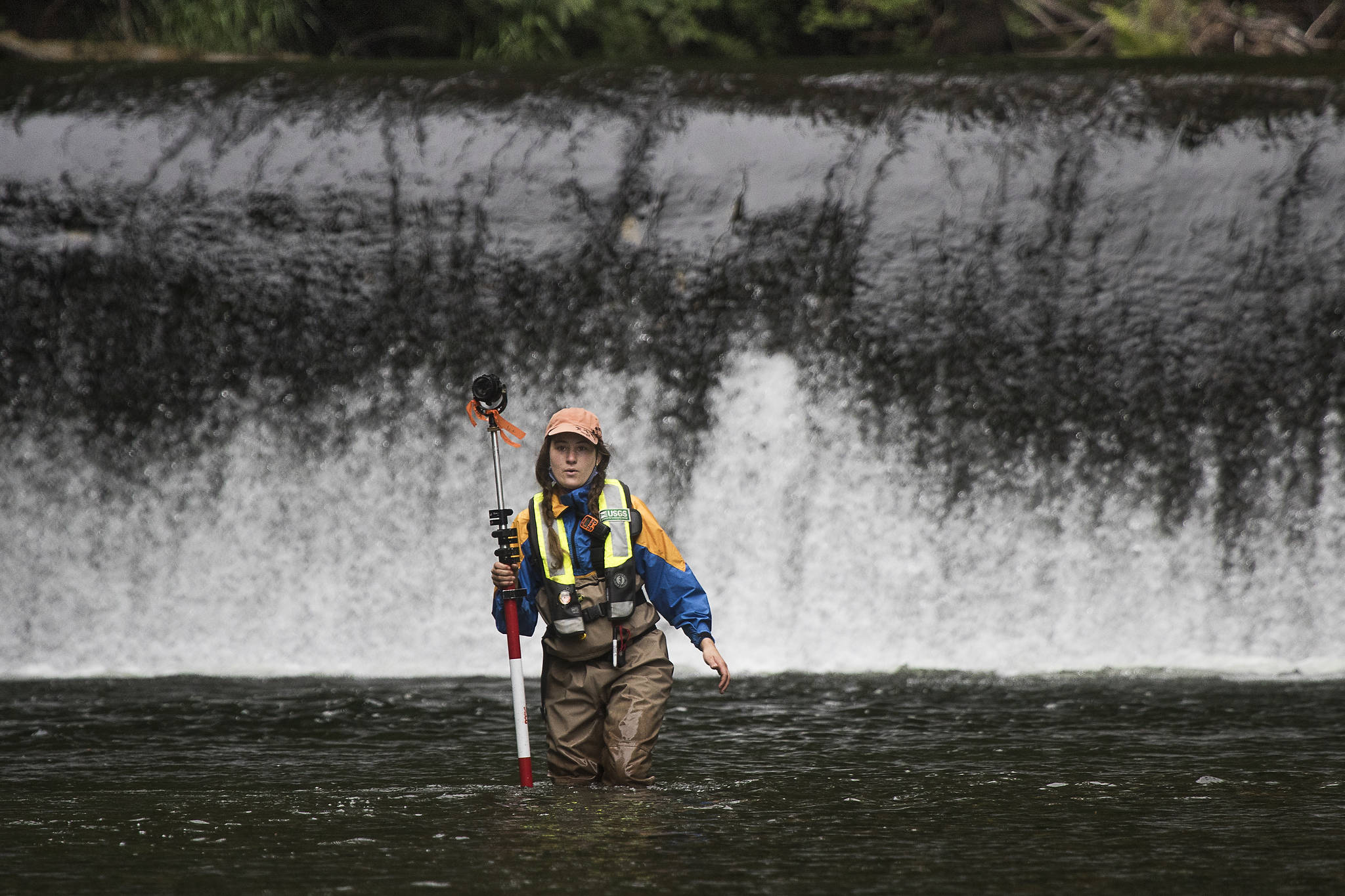 With the Pilchuck Dam behind her, Katie Seguin of the U.S. Geological Survey holds a prism pole while standing in the Pilchuck River on Tuesday in Granite Falls. Crews were mapping the riverbed to track how sediment will move once the dam is removed. (Andy Bronson / The Herald)