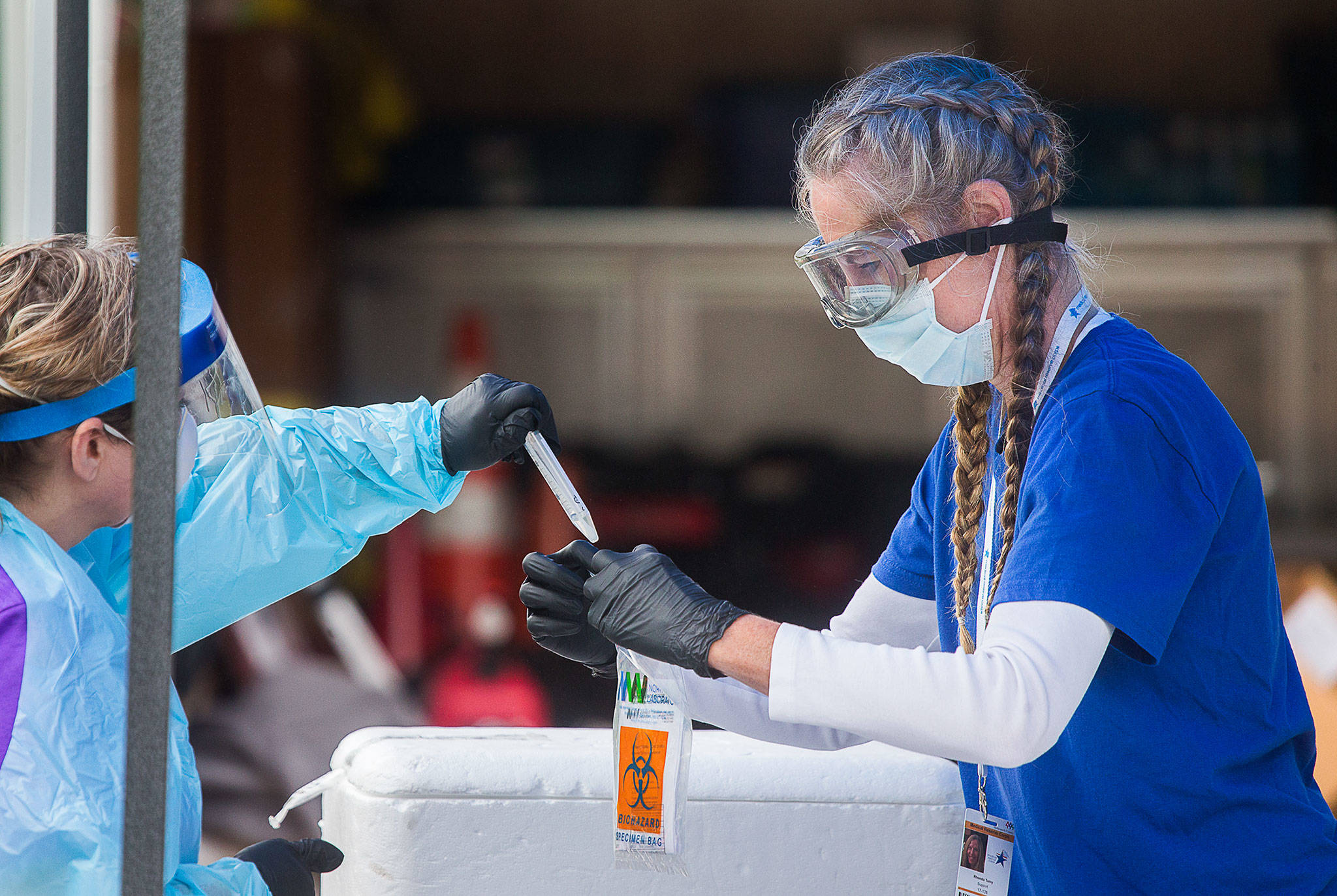 Medical Reserve Corps volunteer Rhonda Tumy collects a sample from a registered nurse at a COVID-19 testing site at McCollum Park in Everett. (Andy Bronson / The Herald)