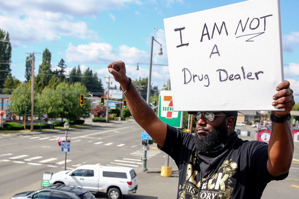 Elton Davis salutes on a rooftop as part of a weekly protest. He’s been charged with a misdemeanor for noise and public nuisance. (Kevin Clark / The Herald)
