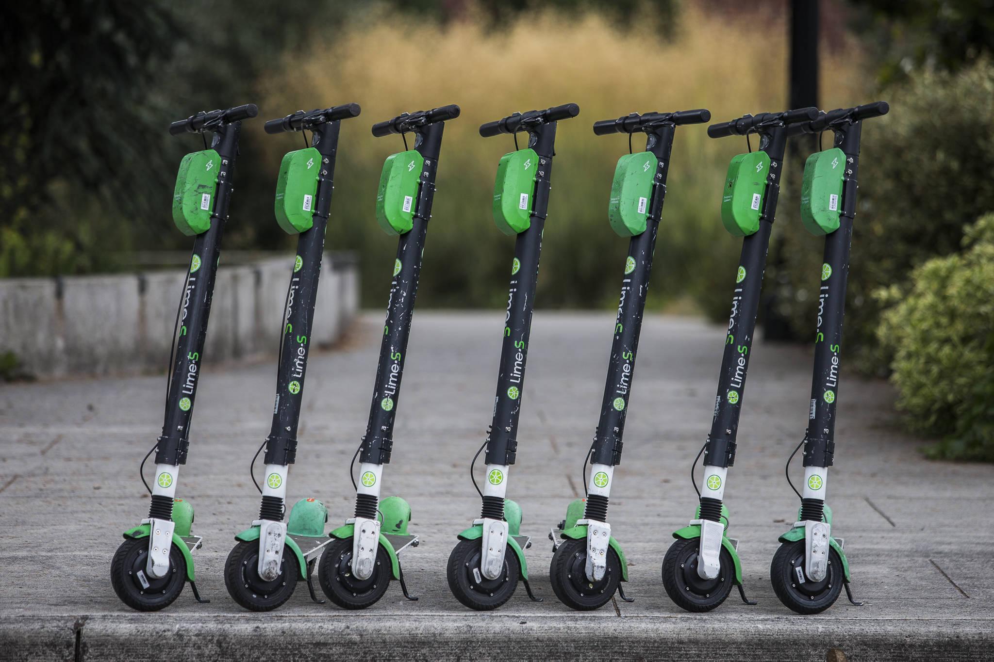 Fully charged Lime scooters along Bothell Way are ready to roll Wednesday in Bothell. (Olivia Vanni / The Herald)