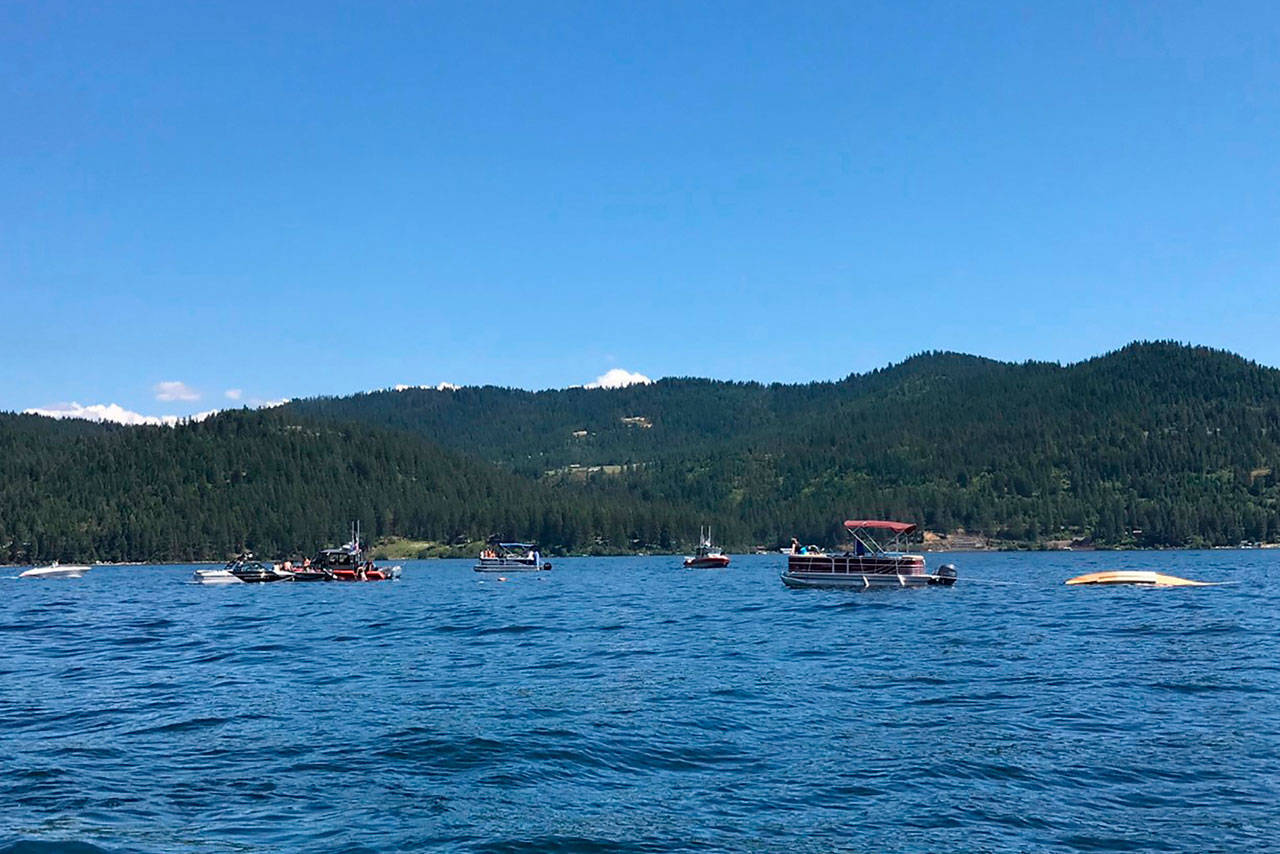 Boaters flag down authorities to a crashed seaplane near Powderhorn Bay on Lake Coeur dAlene on Sunday, south of Coeur dAlene, Idaho. The downed plane can be seen in the right side of the image. (Stephanie Hammett/The Spokesman-Review via AP)