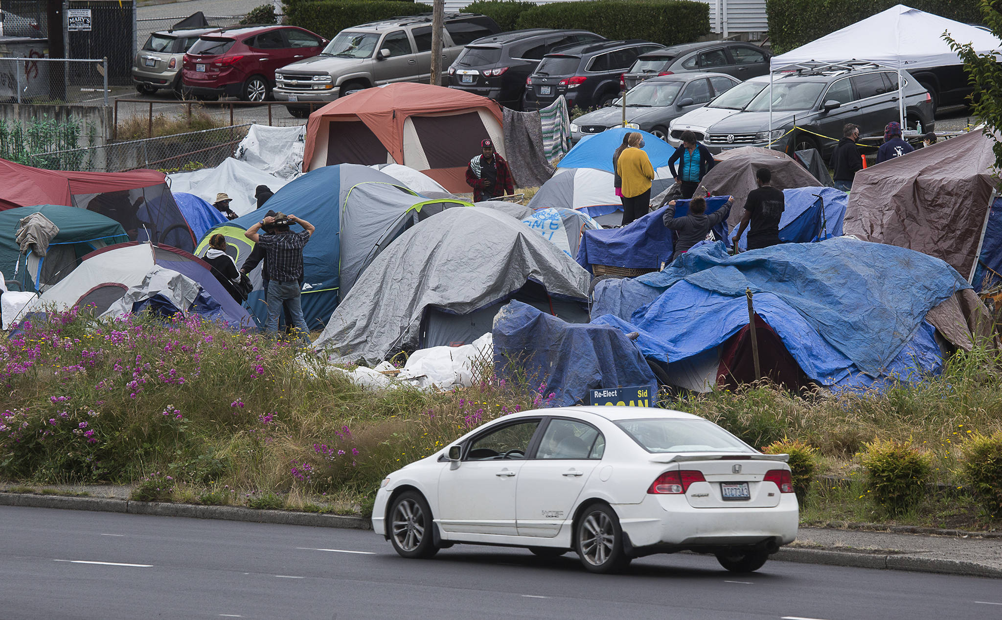 Cars drive by a homeless encampment at 3217 Rucker Ave. on Tuesday in Everett. The camp relocated from the country courthouse plaza. (Andy Bronson / The Herald)