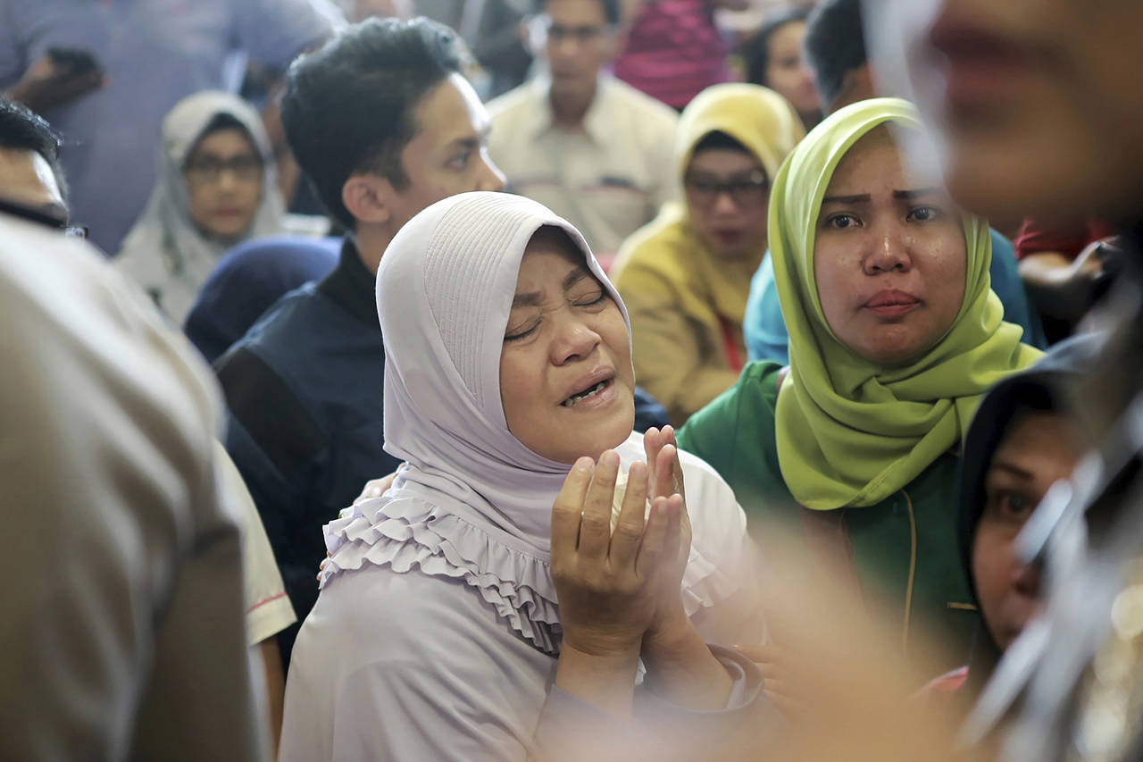 In this Oct. 29, 2018 photo, a relative prays as she and others wait for news on a Lion Air plane that crashed off Java Island at Depati Amir Airport in Pangkal Pinang, Indonesia. (AP Photo/Hadi Sutrisno, File)