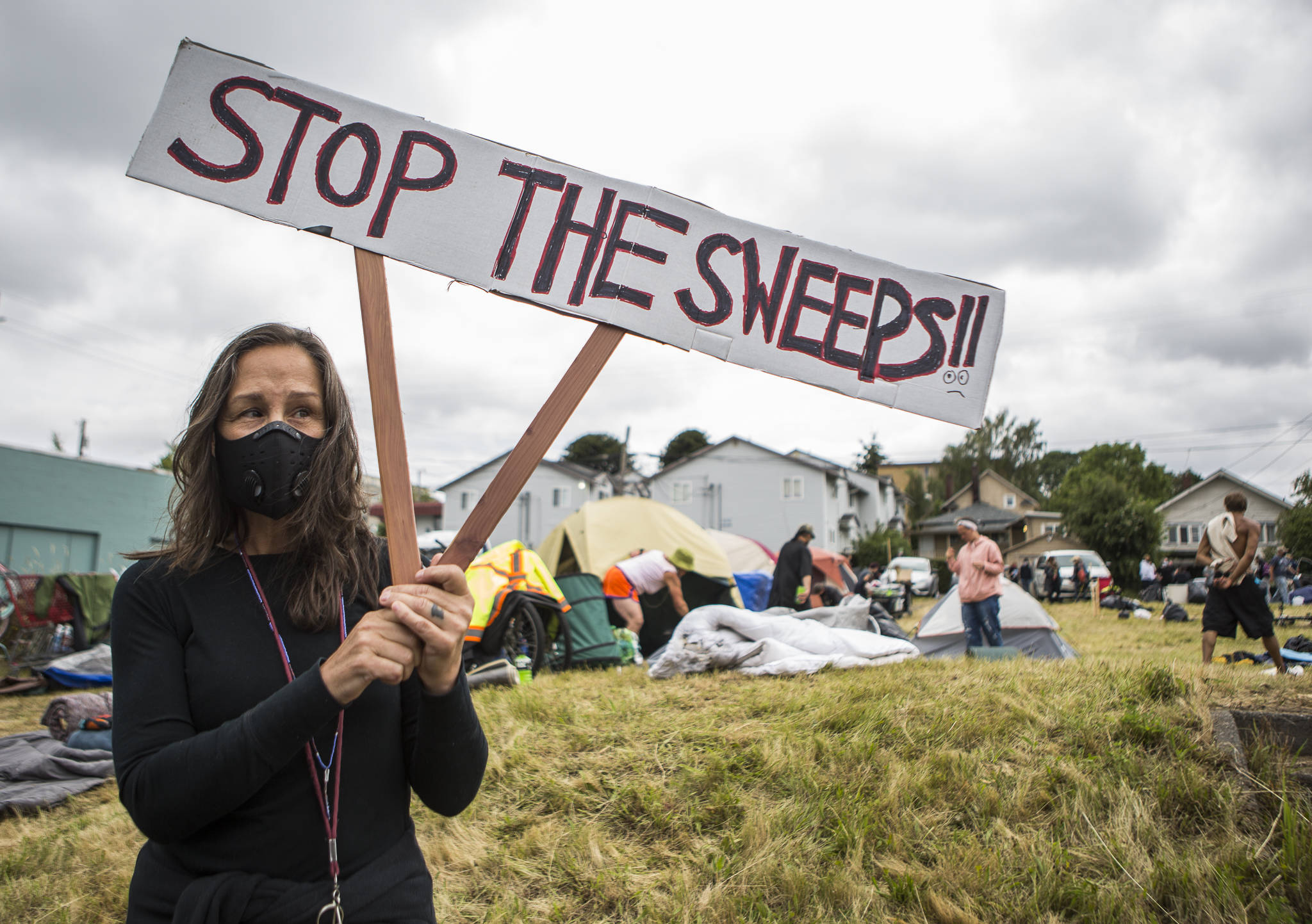 Cathy Decker stands along Rucker Avenue to protest the breakup of a homeless camp on an empty piece of property in Everett on Thursday. (Olivia Vanni / The Herald)