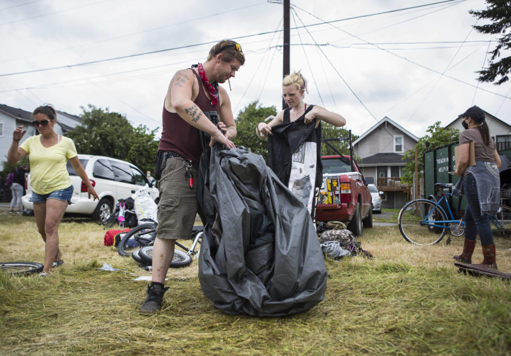 Jack Travis gets help packing up his tent at the Rucker Avenue homeless camp on Thursday in Everett. (Olivia Vanni / The Herald) 
