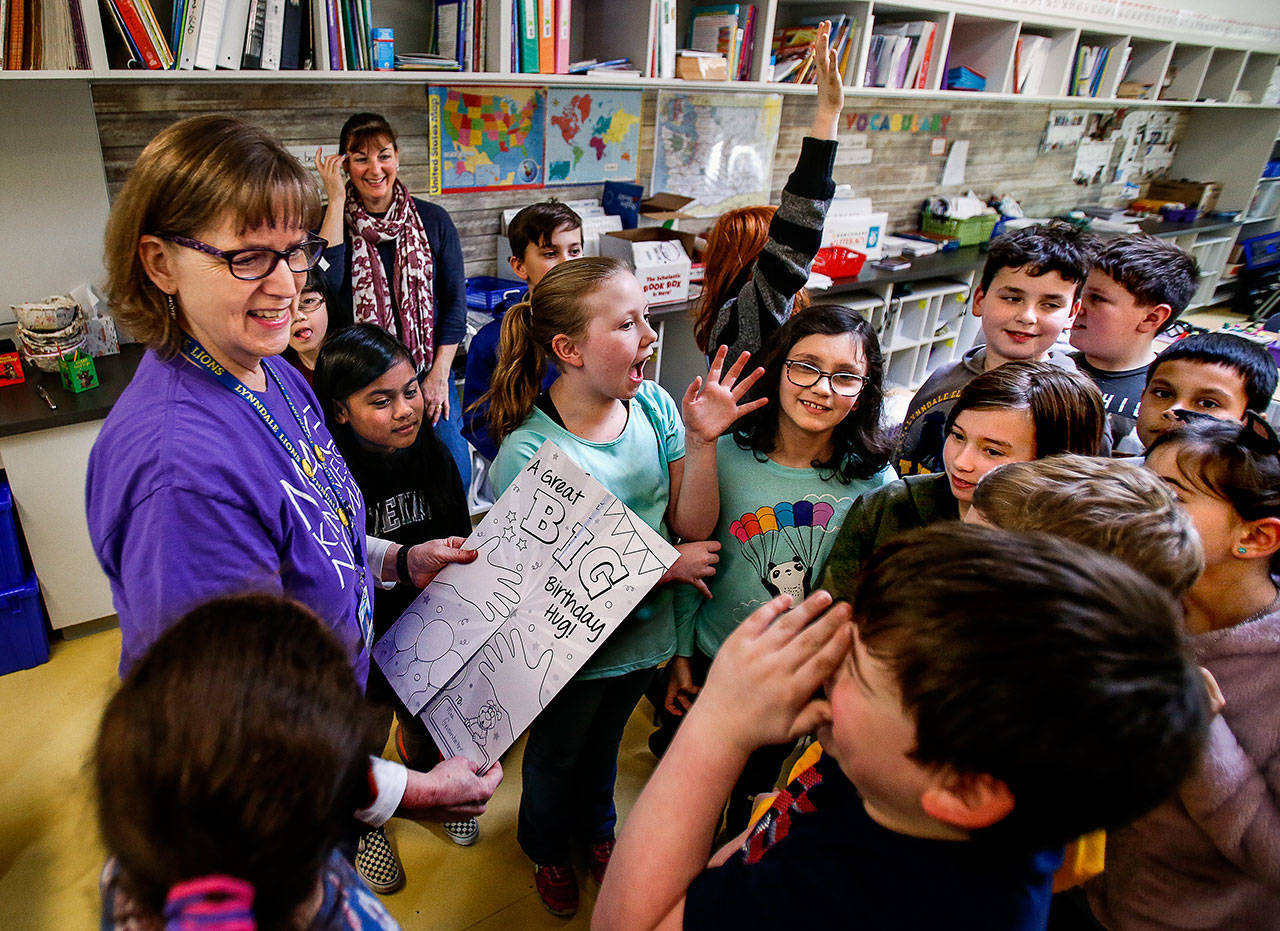 Diane Grossenbacher, office manager at Lynndale Elementary School in Lynnwood, is greeted by third- and fourth-graders celebrating her 15th actual birthday and her 60th on Leap Day, Feb. 29. Scenes like this later this fall will depend on schools’ ability to safely reopen. (Dan Bates / Herald file photo)