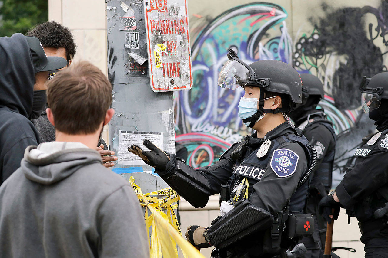 A police officer engages with a protester Wednesday, July 1, 2020, in Seattle, where streets had been blocked off in an area demonstrators had occupied for weeks. (AP Photo/Elaine Thompson)
