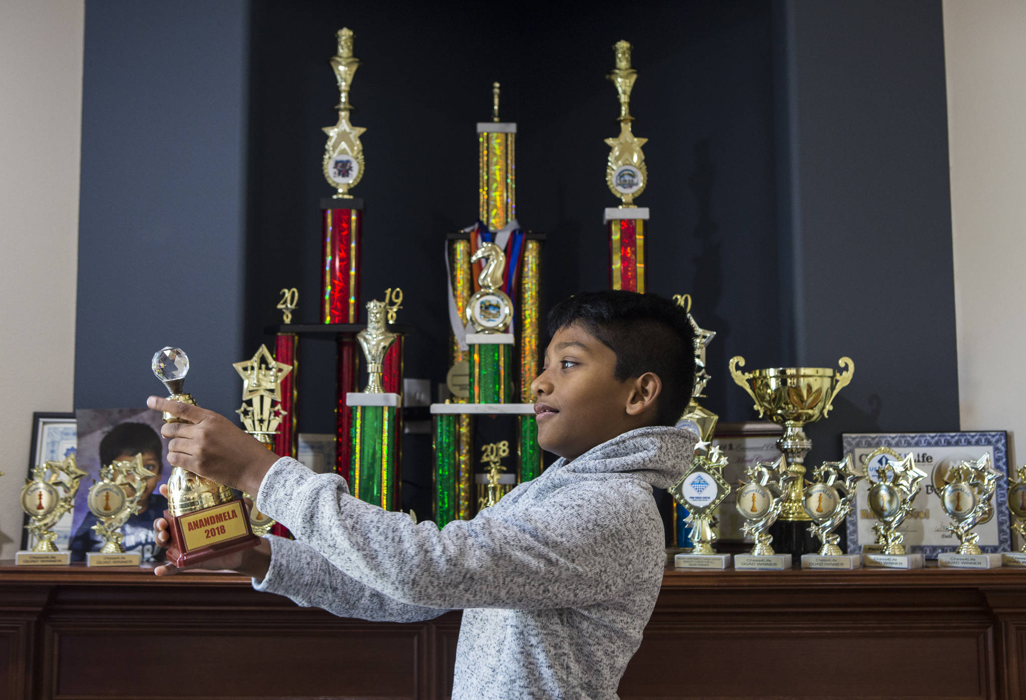 Keshav Beegala, 9, holds up his favorite of 22 trophies and six medals on display in his family’s home in Bothell. (Olivia Vanni / The Herald)