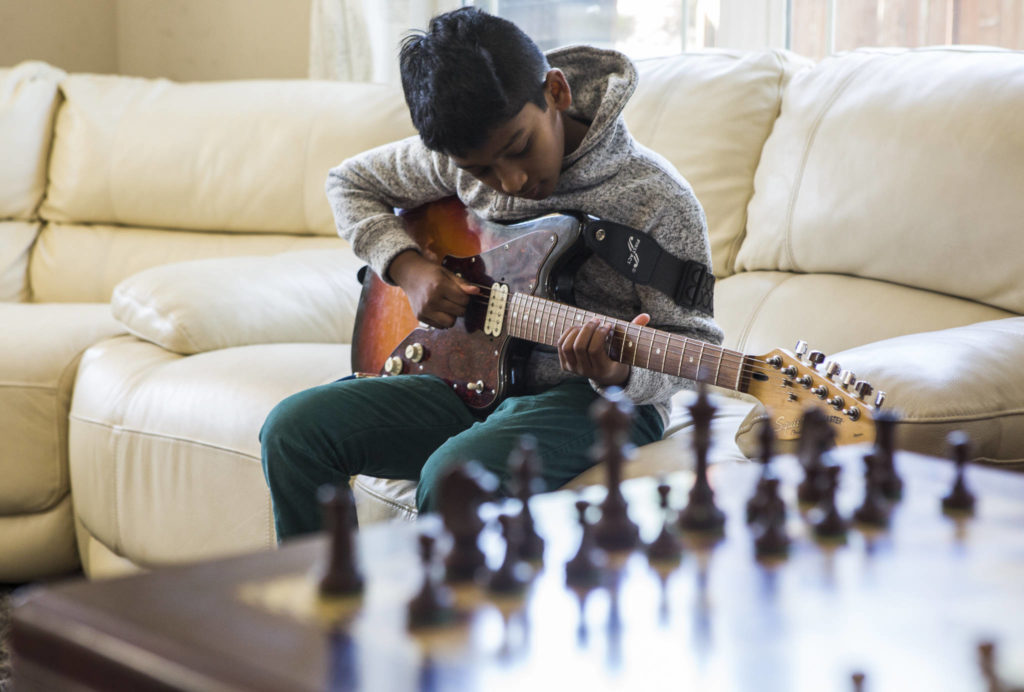 Keshav Beegala plays his guitar at his home in Bothell. (Olivia Vanni / The Herald)
