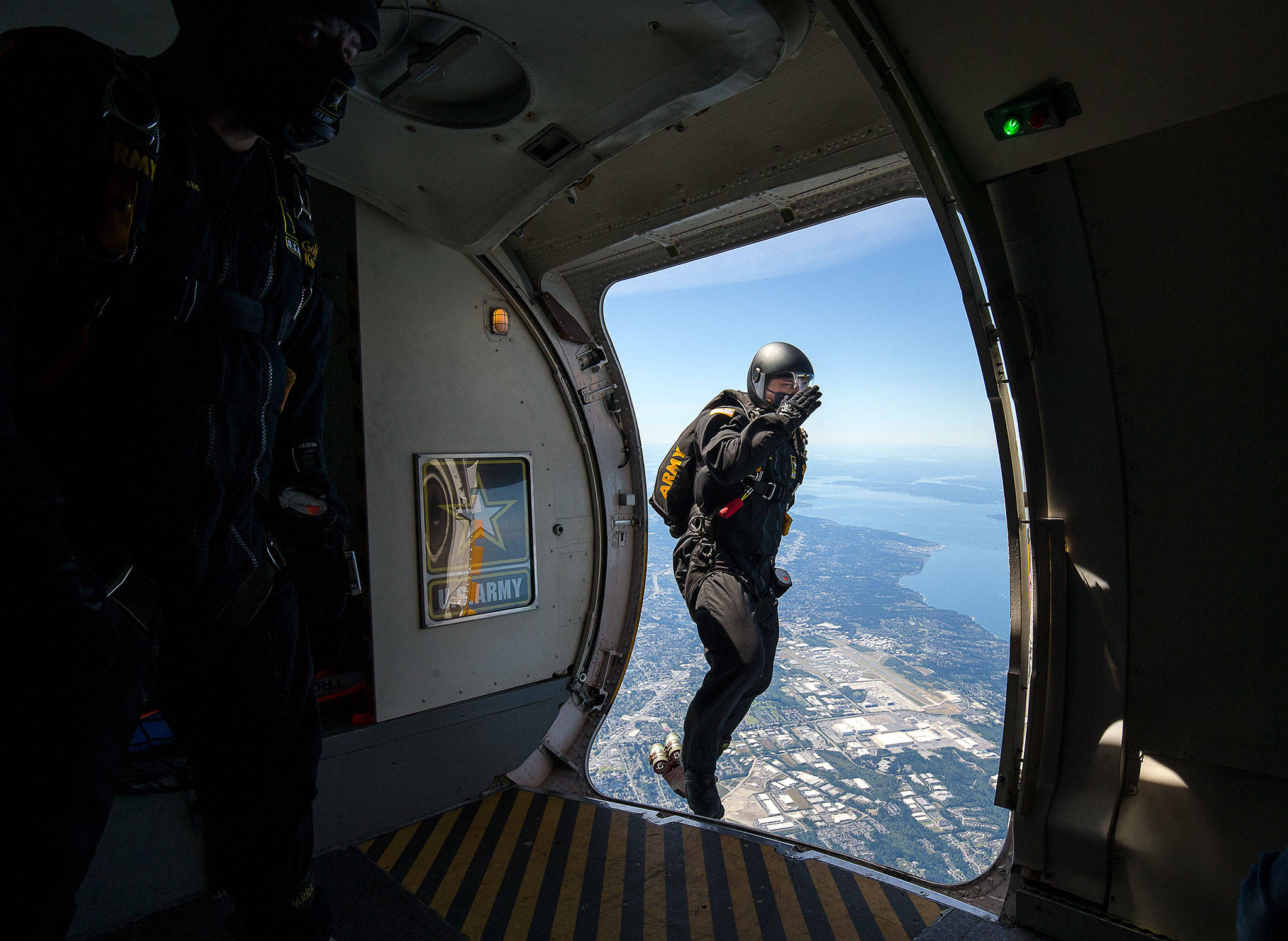 With Paine Field in the background, Dominic Perry of the U.S. Army Golden Knights salutes Tuesday as he parachutes toward Providence Regional Medical Center Everett. The Golden Knights presented a healthcare worker at the hospital with an award, a token of appreciation for their continued efforts. (Andy Bronson / The Herald)