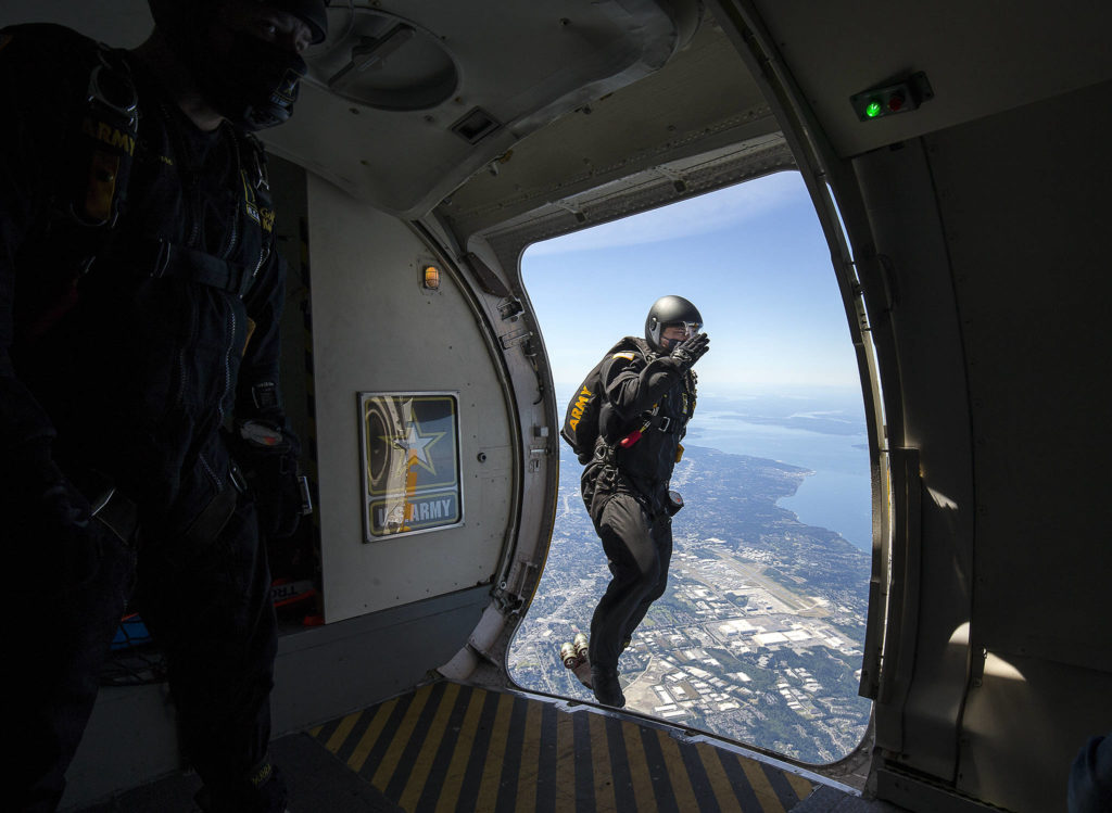 With Paine Field in the background, Dominic Perry of the U.S. Army Golden Knights salutes Tuesday as he parachutes toward Providence Regional Medical Center Everett. The Golden Knights presented a healthcare worker at the hospital with an award, a token of appreciation for their continued efforts. (Andy Bronson / The Herald)
