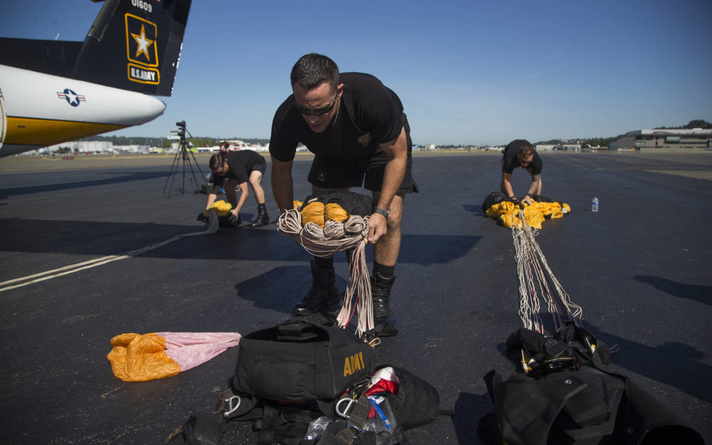 Ryan Reis, of Tacoma, packs his parachute as the U.S. Army Golden gets ready to drop into Providence Regional Medical Center in Everett on Tuesday. (Andy Bronson / The Herald)
