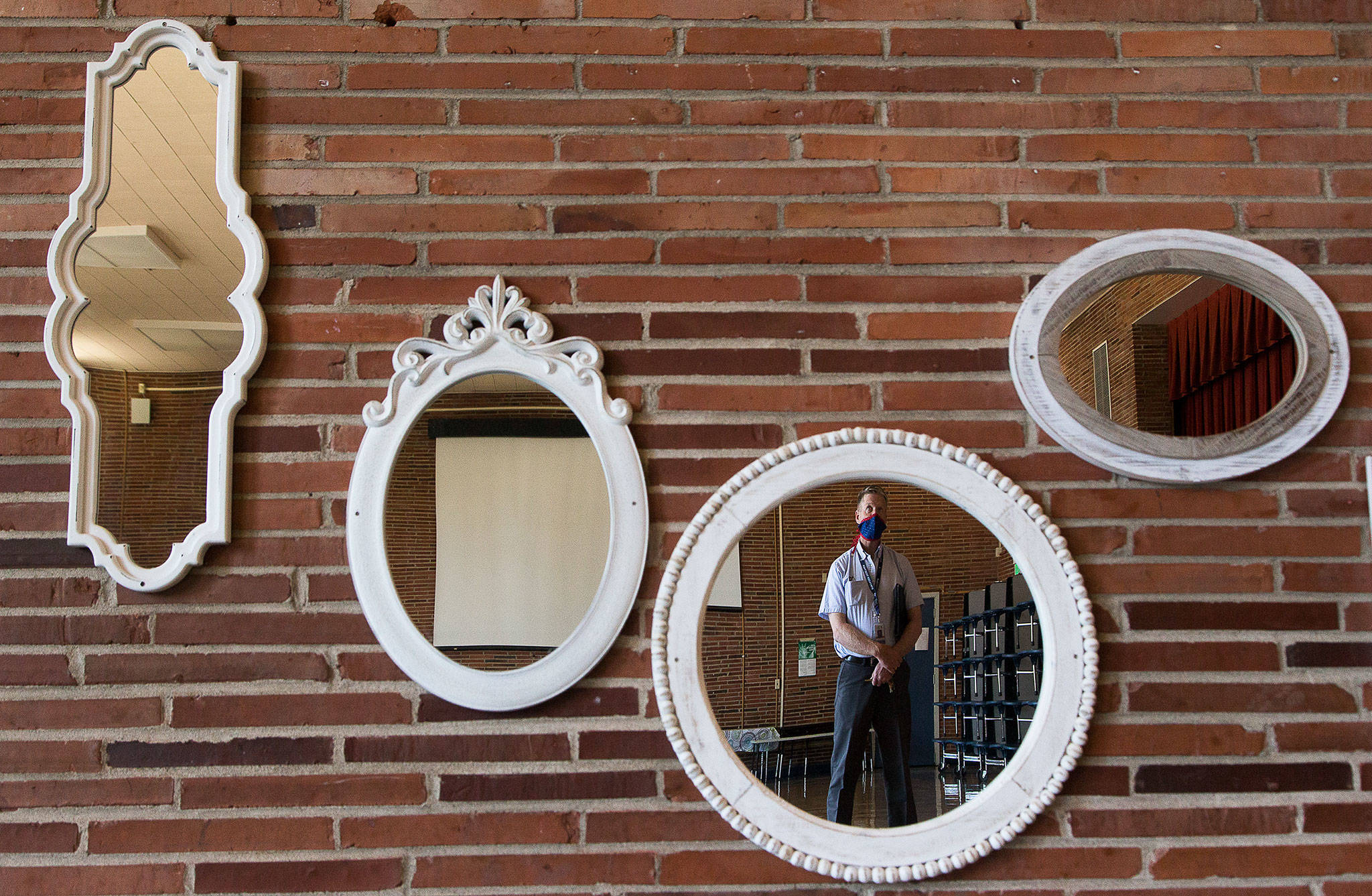 Director of Facilities and Planning Darcy Walker is reflected in a mirror mounted on unreinforced masonry brick in the cafeteria at Madison Elementary, one of several Everett schools up for replacement on the upcoming bond vote, on Wednesday in Everett. (Andy Bronson / The Herald)