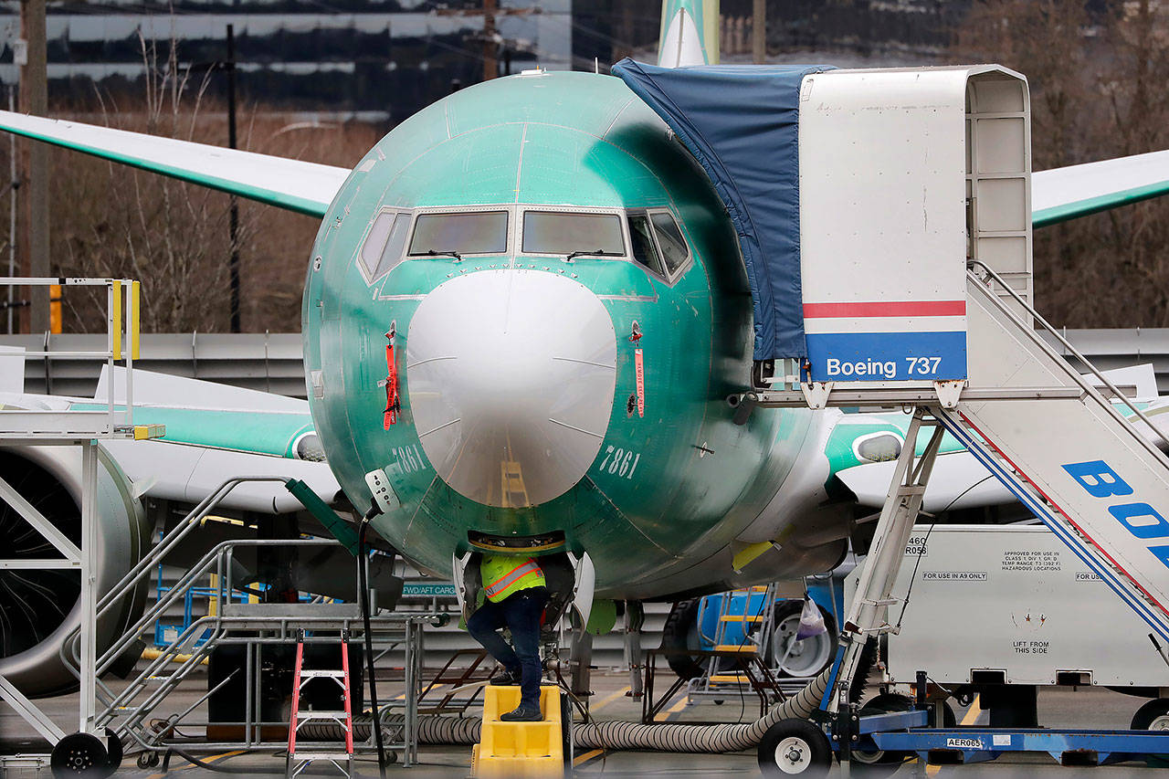 In this December 2019 photo, a worker looks up underneath a Boeing 737 Max jet in Renton. (AP Photo/Elaine Thompson, File)