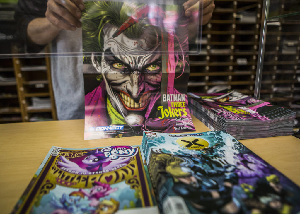 A poster along with two free comics at Everett Comics as part of Free Comic Book Summer. The blockbuster annual event that was Free Comic Book Day was changed this year due to the pandemic and now spans two months. (Olivia Vanni / The Herald). 

