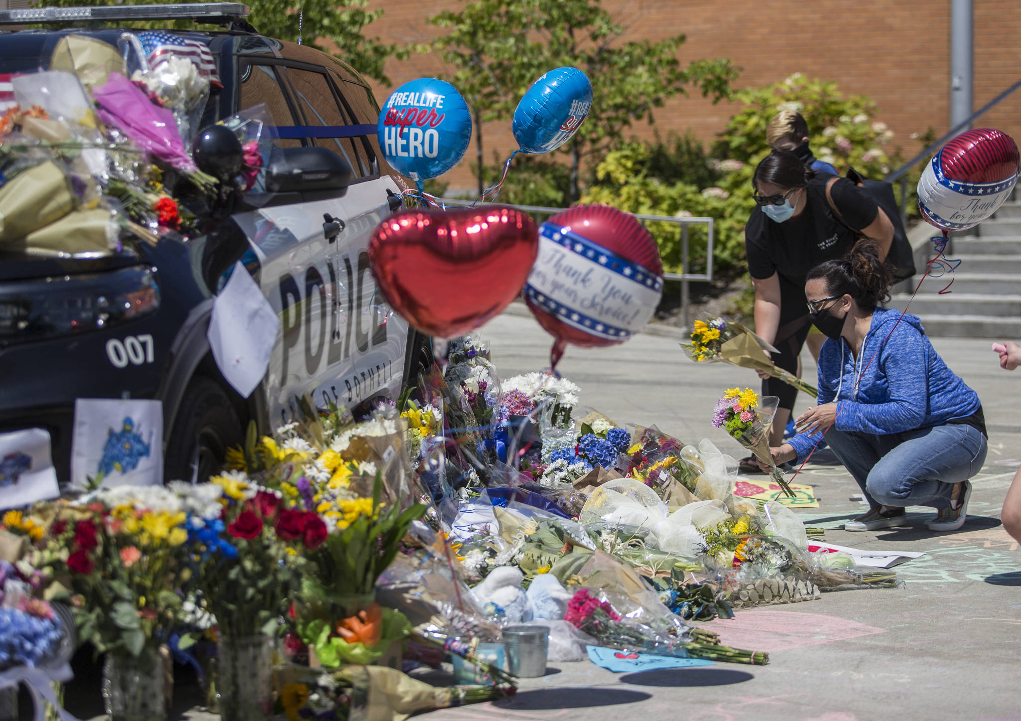 People place flowers at a memorial in front of Bothell City Hall on Tuesday for Officer Jonathan Shoop, who was killed in the line of duty Monday night. (Olivia Vanni / The Herald)