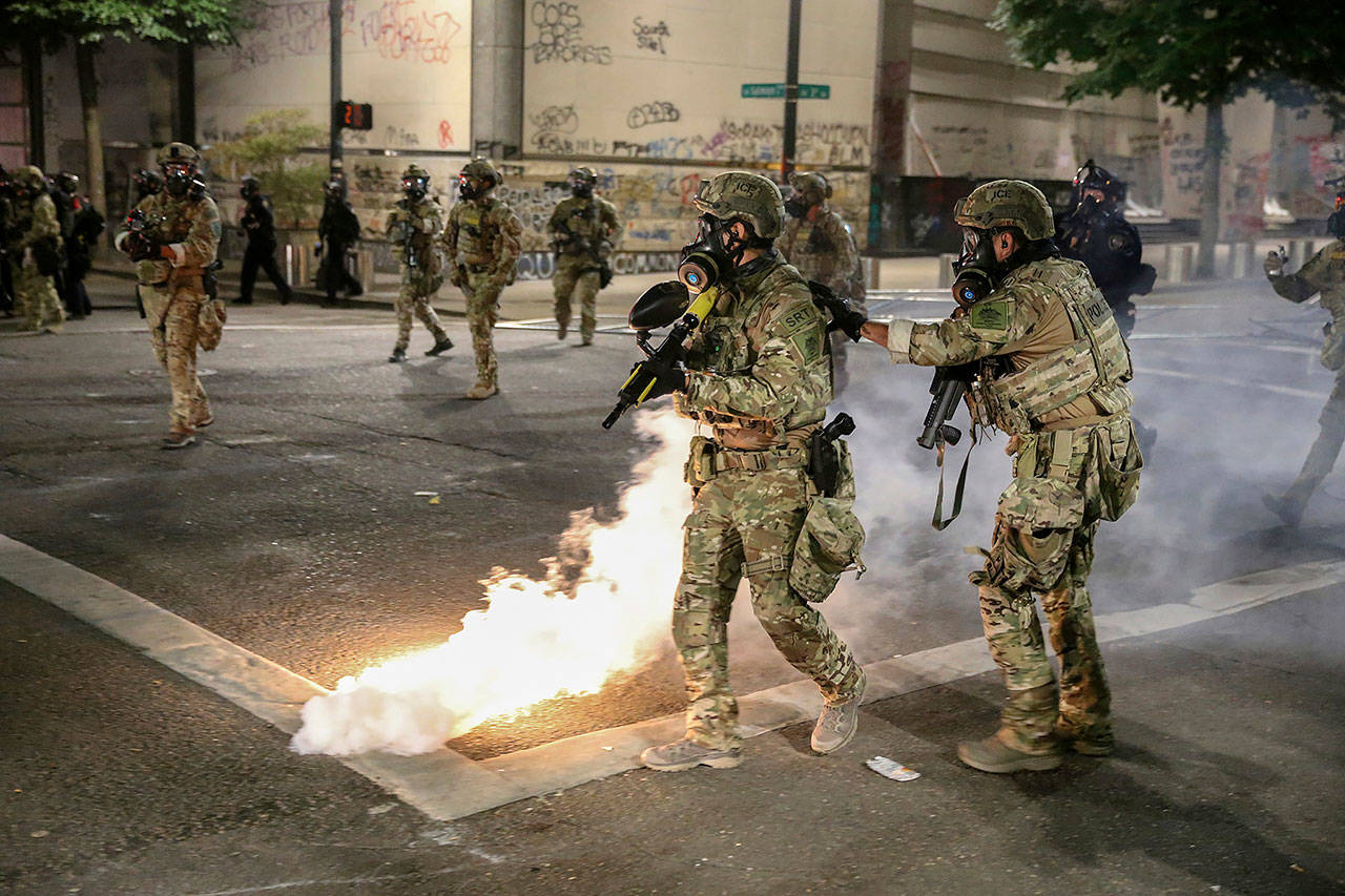 Police respond to protesters during a demonstration Friday in Portland, Oregon. Militarized federal agents deployed by the president to Portland, fired tear gas against protesters again overnight as the city’s mayor demanded that the agents be removed and as the state’s attorney general vowed to seek a restraining order against them. (Dave Killen/The Oregonian via AP)