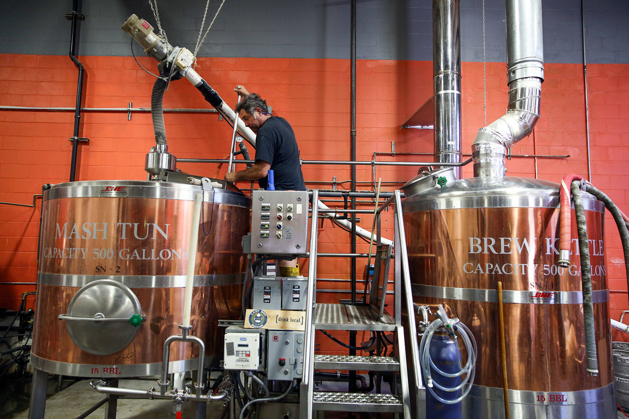 Shawn Loring, owner of Lazy Boy Brewing, works the vats at his shop Saturday afternoon in Everett. (Kevin Clark / The Herald)