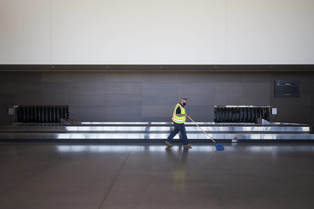 Terminal duty manager Tom Hoctor sweeps the baggage pickup area as he helps prepare for passenger service to return Saturday at Paine Field. (Andy Bronson / The Herald)
