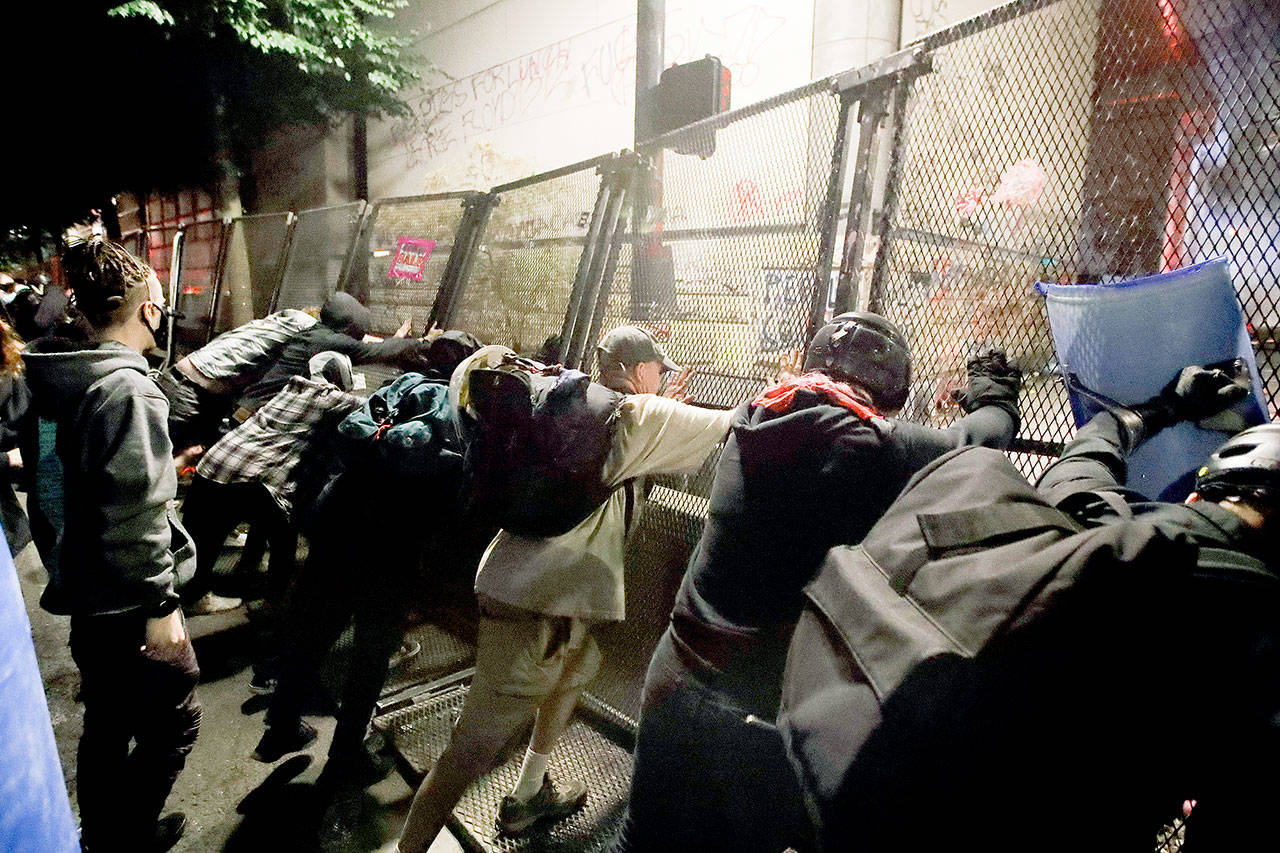 Demonstrators try to topple a steel fence during a Black Lives Matter protest at the Mark O. Hatfield United States Courthouse Saturday in Portland. (AP Photo/Marcio Jose Sanchez)