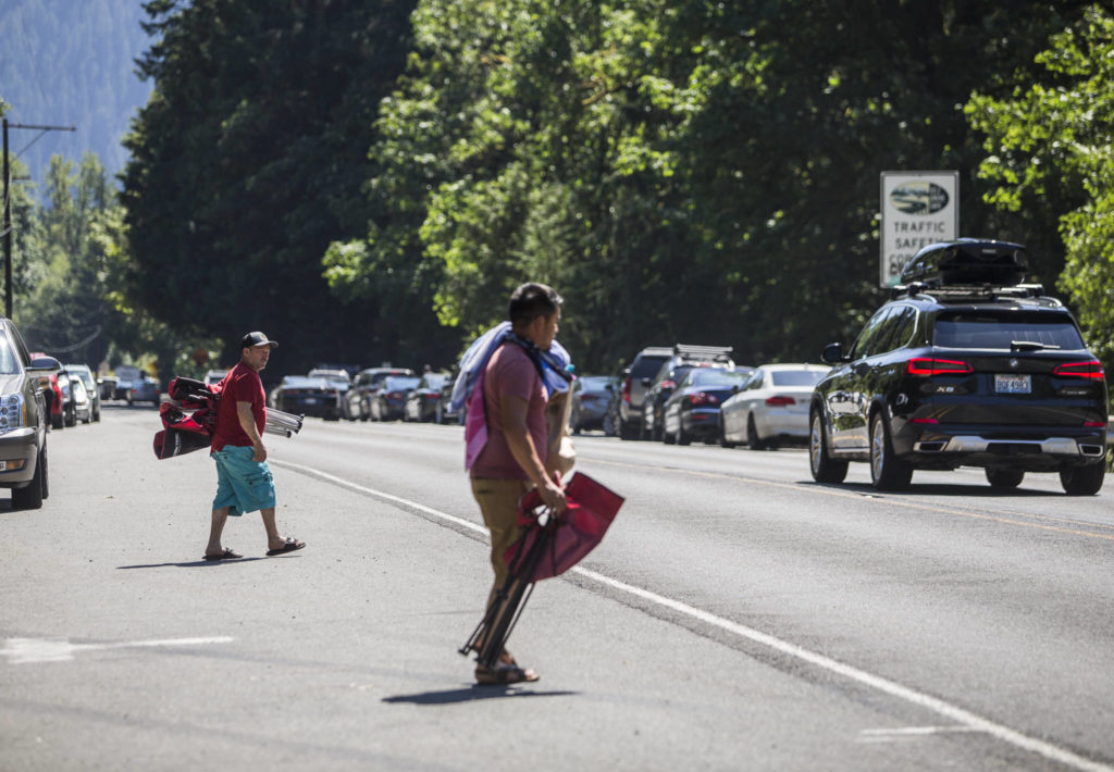 People wait for cars to pass before crossing U.S. 2 to get to Eagle Falls on Wednesday in Index. (Olivia Vanni / The Herald)
