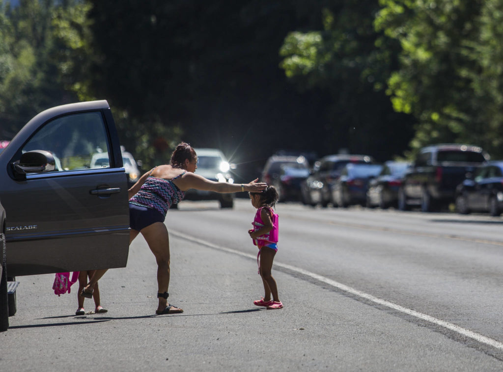 A woman reaches out to pull a young girl away from the fog line along U.S. 2 as cars speed by Wednesday in Index. (Olivia Vanni / The Herald)
