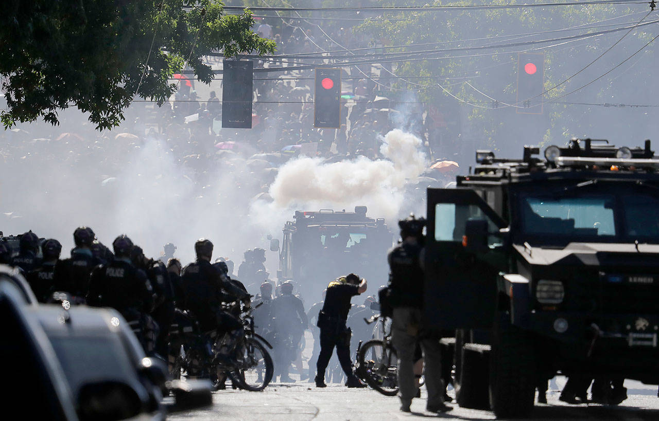 Smoke rises as police clash with protesters Saturday during a Black Lives Matter protest near the Seattle Police East Precinct headquarters. (AP Photo/Ted S. Warren)
