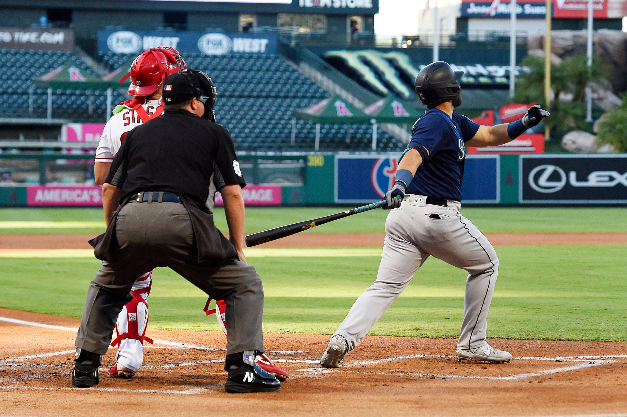 The Mariners’ Jose Marmolejos (right) hits a three-run home run as Angels catcher Max Stassi watches during the first inning of a game July 30, 2020, in Anaheim, Calif. (AP Photo/Mark J. Terrill)