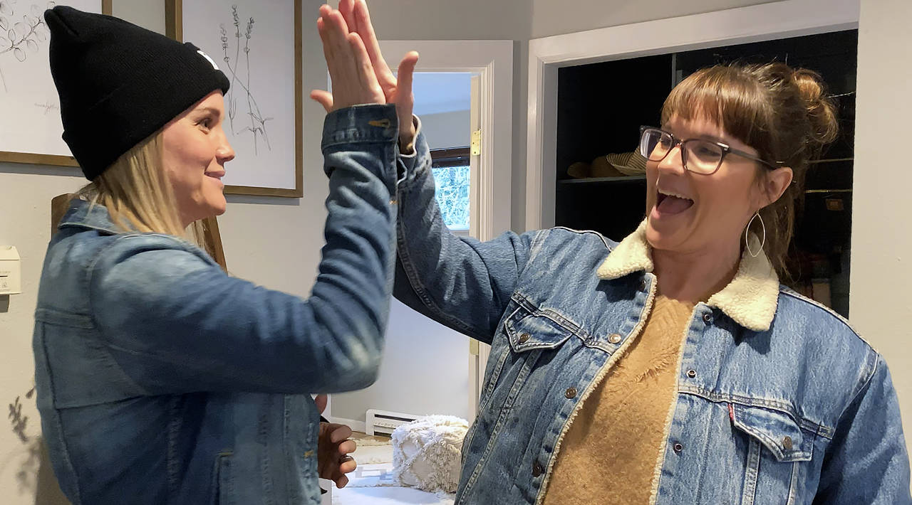 Snohomish twins Leslie Davis (left) and Lyndsay Lamb give each other a high five at an Everett home makeover for HGTV. (Sue Misao / The Herald)