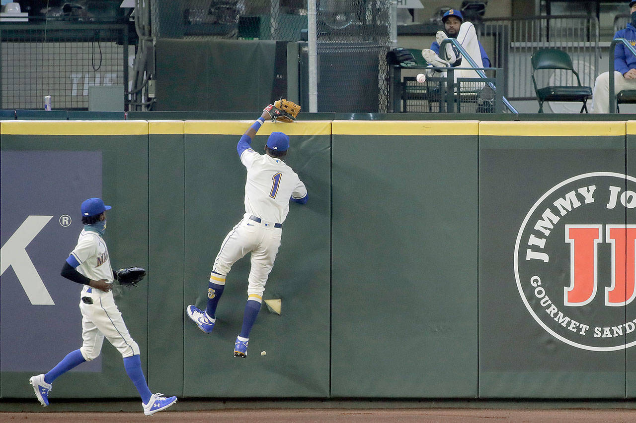 Seattle Mariners right fielder Kyle Lewis jumps at the wall but can’t get to a three-run home run hit by Oakland Athletics’ Ramon Laureano during the fifth inning of Sunday’s game in Seattle. Mariners left fielder Dee Gordon looks on at left. (AP Photo/Ted S. Warren)