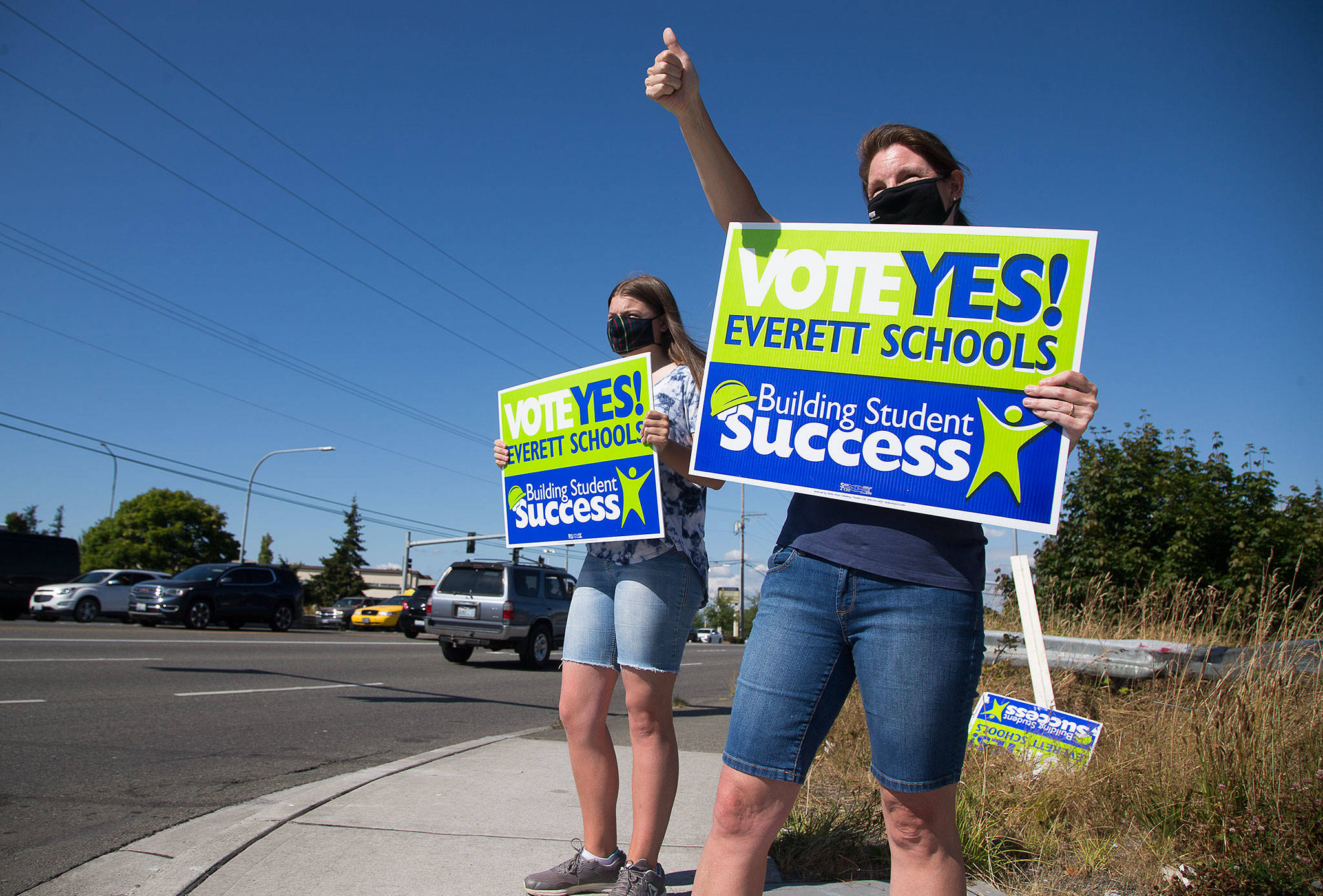 Jen Hirman and her daughter, Elizabeth, who attends Jackson High School, wave signs along Evergreen Way on Monday in support of the Everett schools levy. (Andy Bronson / The Herald)