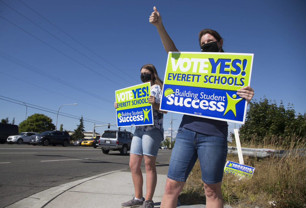 Jen Hirman and her daughter, Elizabeth, who attends Jackson High School, wave signs along Evergreen Way on Monday in support of the Everett schools levy. (Andy Bronson / The Herald)
