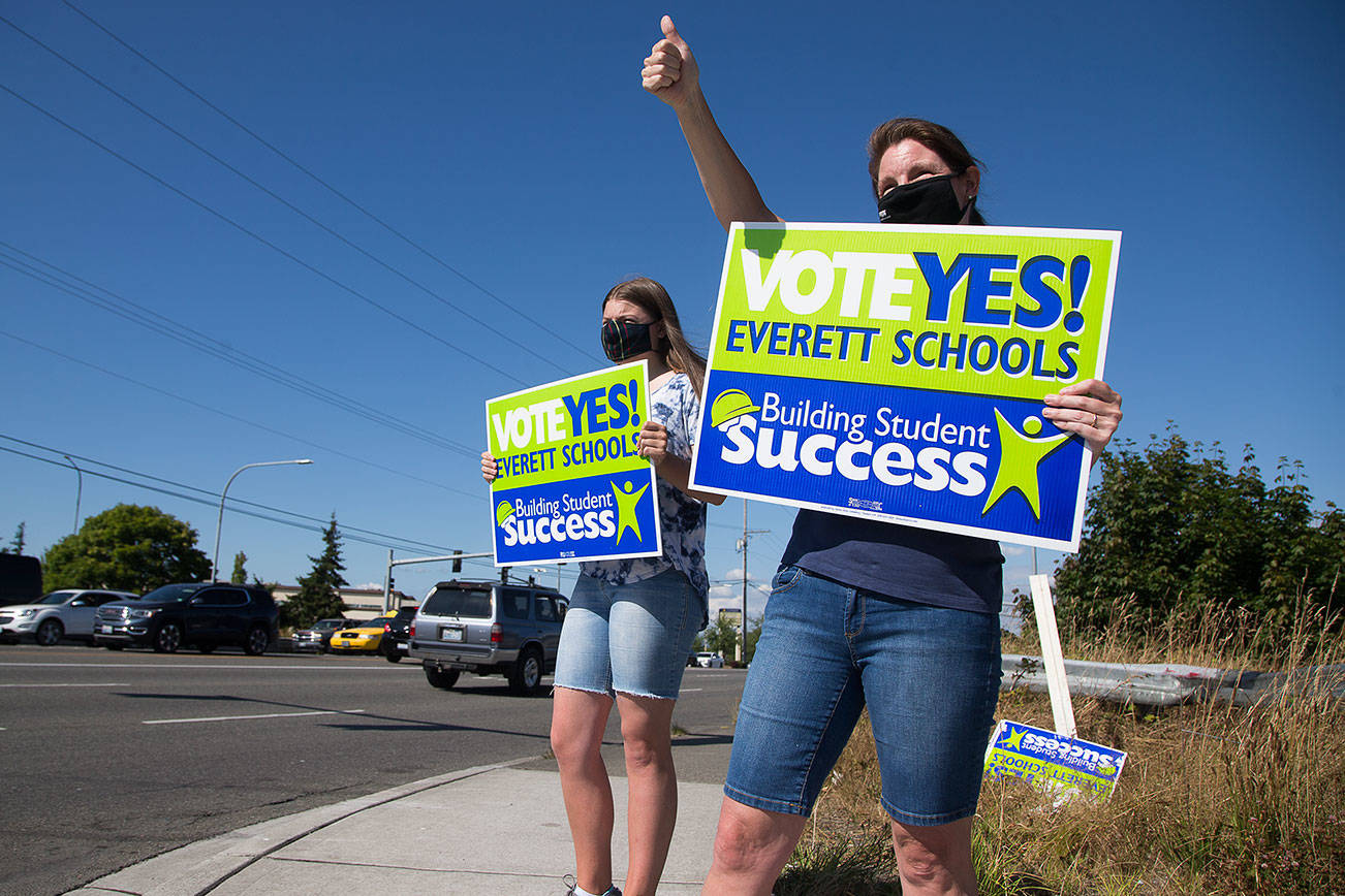 Jen Hirman and her daughter Elizabeth, who attends Jackson High, waves signs along Evergreen Way in support of the Everett schools levy on Monday, Aug. 3, 2020 in Everett, Wa. (Andy Bronson / The Herald)