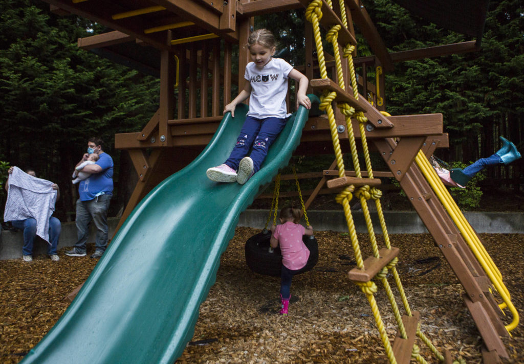 Chelsea Dunning, 5, goes down a slide Thursday while sisters Ella Dunning, 3, and Briana Dunning, 7, play on the swings in Everett. Both Chelsea and Brianna finished the online Early Childhood Education and Assistance Program. (Olivia Vanni / The Herald)
