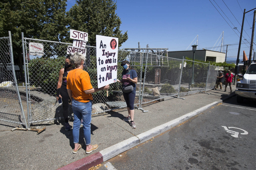 Men put up fencing at Matthew Parsons Park in Everett on Wednesday as protesters talk. (Andy Bronson / The Herald)
