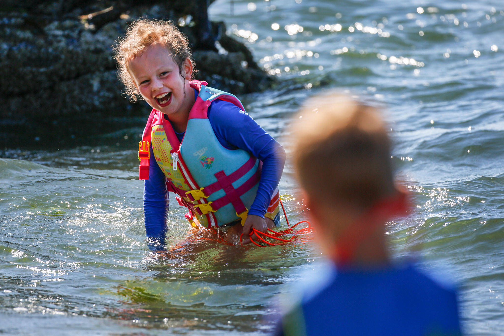 Piper Hounsel, 7, (left) shares a laugh with her brother Weston Hounsel, Friday afternoon in the waters off Howarth Park in Everett on August 14, 2020. (Kevin Clark / The Herald)